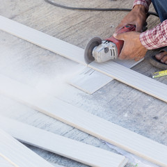 carpenter hands using electric saw on wood at construction site