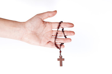 Brown rosary hanging on a female hand on white background