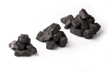 Three small piles of black coal on a white glossy background