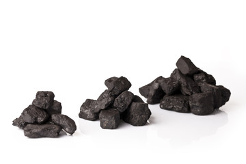 Three small piles of black coal on a white background