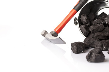 Silver bucket with some lumps of black coal and the mining pickax in focus