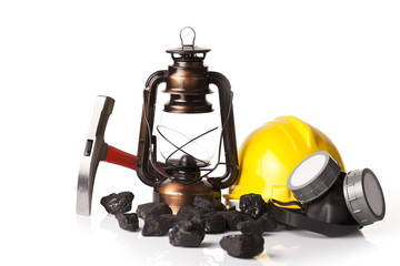 Old mining lamp with yellow helmet, mining pickax, dust mask and loose lumps of black coal