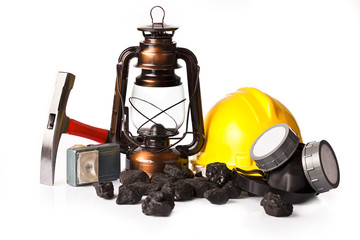Old mining lamp with yellow helmet, electric torch, mining pickax, dust mask and loose lumps of black coal