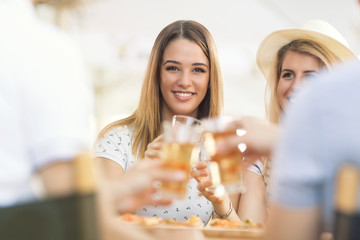 Beautiful young woman toasting with her friends at the pizzeria