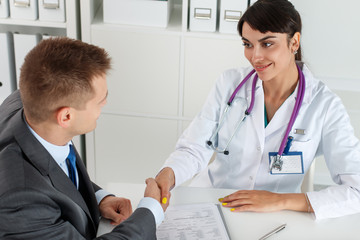 Beautiful smiling female medicine doctor shaking hands with male
