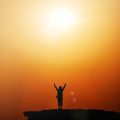 Silhouette of traveller with hands raised to the sun at  sunrise