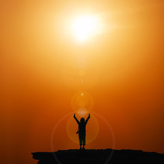 Silhouette of traveller with hands raised to the sun with flare