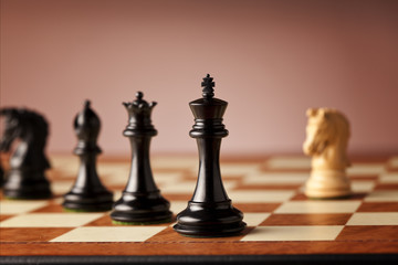 Overwhelming advantage - main black chess pieces facing single white knight on a luxurious traditional wooden chessboard