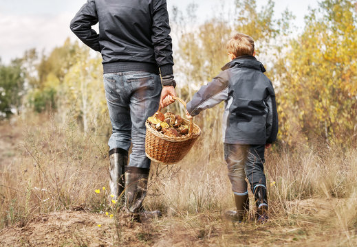 Father and son carry full basket of mushrooms
