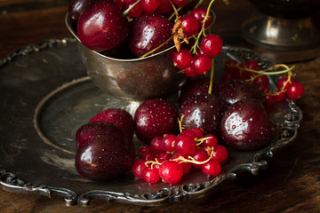 cherry with red currants in a bowl and a metal plate in oriental