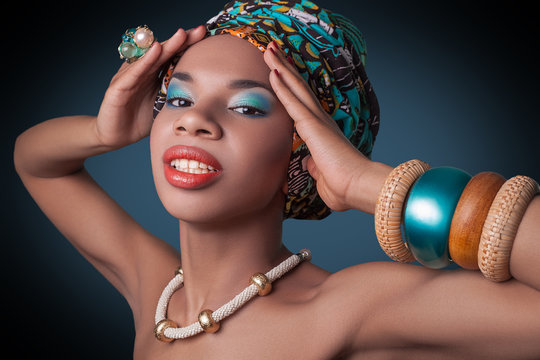 young beautiful fashion model with traditional african style with scarf, earrings and makeup on dark blue background.  
Developed from RAW, edited with special care and attention. 
