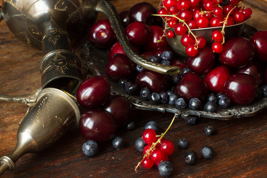 cherry with red currants and blueberries in a jug and a metal pl