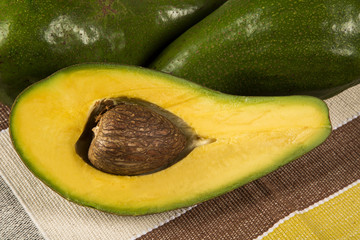 Two whole avocados and a avocado cut in a half over a white surf