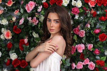 Attractive young woman in white dress on flower wall