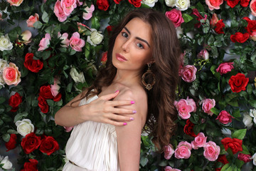 Obraz na płótnie Canvas Attractive young woman in classy white dress on flower wall
