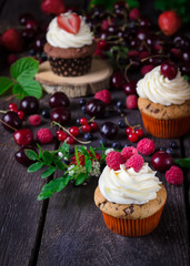 Cupcakes and berries on dark wooden background.