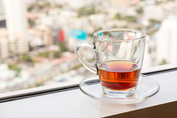 a glass with tea at the window with soft blur city view in background