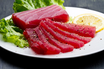 Slices of raw bluefin tuna  sashimi on white dish on wood backgr - obrazy, fototapety, plakaty