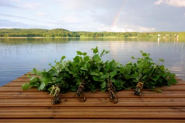  Traditional Finnish bath whisks made out of fresh birch leaves and twigs on a wet jetty by the lake on a Midsummer Eve. © Mikko Palonkorpi