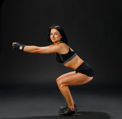 Woman in black fitness suit doing squatting