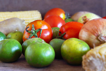 Organic Ingredients on Wooden Background, Onion, Tomato, Lemon, and Corn.