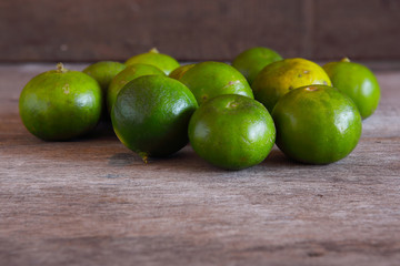 Fototapeta na wymiar Green Lemons on Wooden Background.