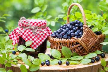 Fototapeta na wymiar Jars of jam and basket with wild blueberries