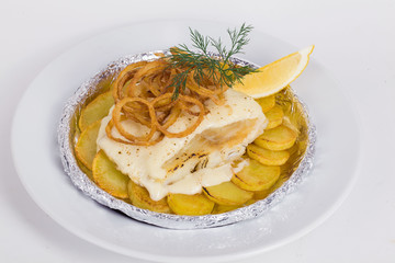 white fish with potatoes, fried onions, dill, lemon in foil on