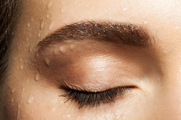 Close-up of closed eye eyelashes and eyebrows brown with water drops