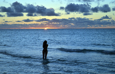 Fototapeta na wymiar Pretty girl photographs Caribbean sunset at Varadero beach, Cuba