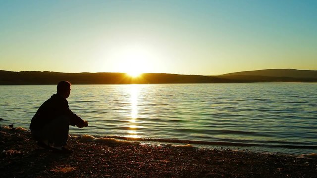 A Man Throwing Pebbles Into Water