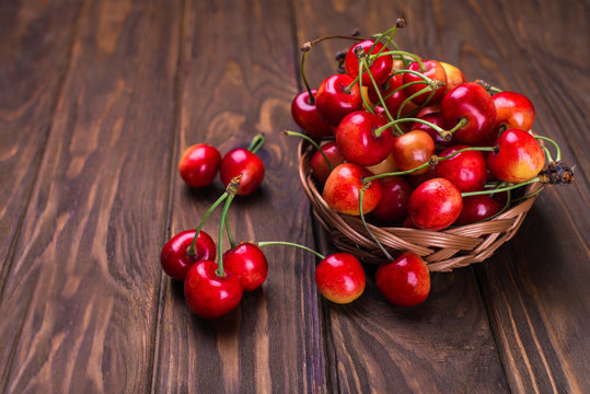 Ripe cherries on wooden table in a basket on the right sight