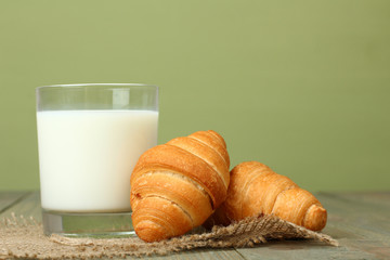 Croissants and milk on wooden background