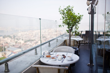 breakfast with cup of black coffee, musli and yoghurt on balcony