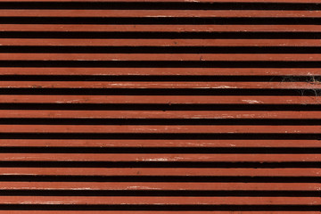 Obraz premium A red striped bulding detail with a web on it. Made out of wood 