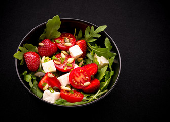 Strawberry tomato salad with feta cheese, olive oil on black