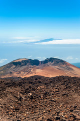 Crater of Pico Viejo volcano on a blue cloudscape background. Multicolored outdoors image.