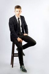 A young boy, brunette with short hair, a student in a black suit