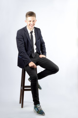 A young boy, brunette with short hair, a student in a black suit