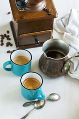 Cups of coffee, coffee pot and coffee grinder.