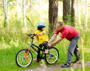 Fototapeta na wymiar father teaching his daughter to ride a bike