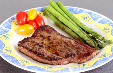 served delicious piece of medium grilled beef steak with tomatos, asparagus
