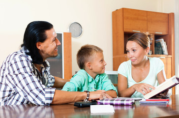 Smiling couple with teenager son doing homework