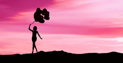 Girl running with balloons at sunset