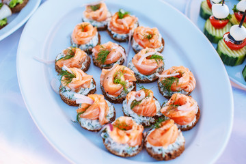 Snacks with salmon on white plate.