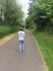 Young girl hikes down wooded trail
