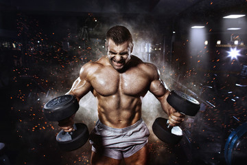 Athlete muscular bodybuilder in the gym training with dumbbells