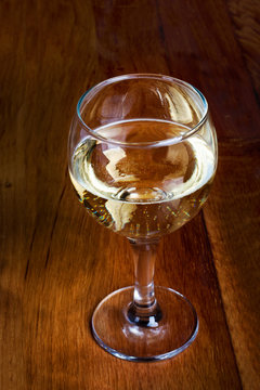 A glass of white wine on wooden top