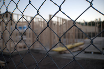 house construction site of a timber frame behind a wire mesh fence