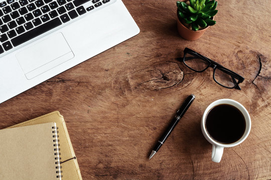 Laptop with notebook and cup of coffee on old wooden table